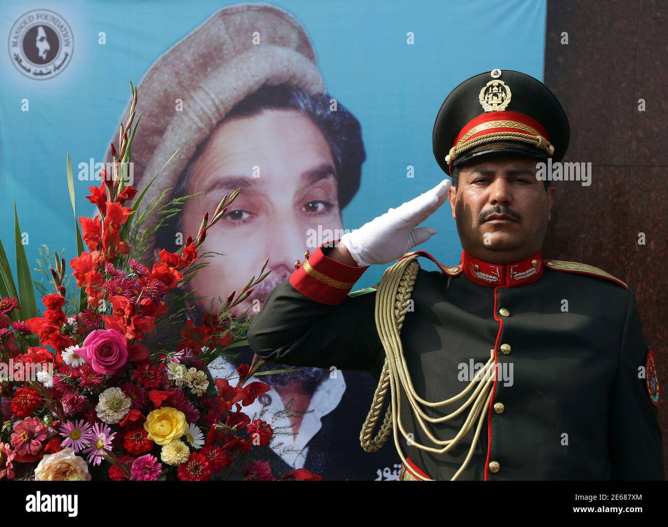 Eine afghanische Ehre bewachen salutiert neben einen Kranz aus Blumen während einer Zeremonie anlässlich der 12. Todestag des ermordeten afghanischen Nationalhelden Ahmad Shah Masood in Kabul 9. September 2013. Masood oder Löwe von Panjshir gekämpft die Taliban an der Spitze der Nordallianz Afghanistan ethnischen Minderheiten, bis zu seiner Ermordung zwei Tage vor den Anschlägen des 11. September 2001 vertreten. REUTERS/Omar Sobhani (AFGHANISTAN - Tags: Jubiläums-Politik-Militär) Stockfoto