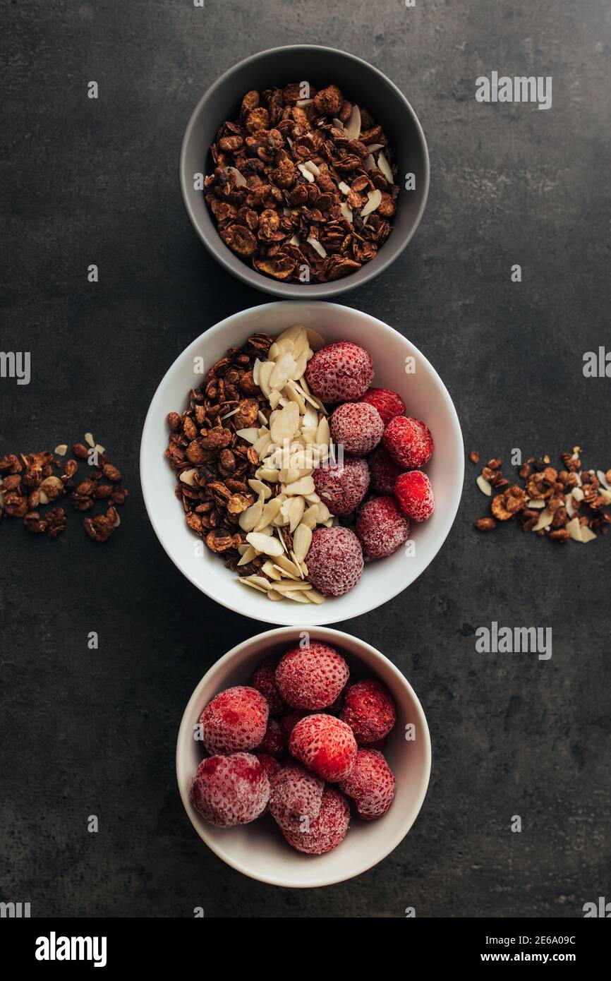 Gefrorene Erdbeere mit Granola, Mandelflocken auf Betontisch Stockfoto