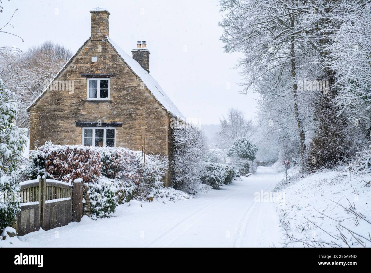 Landstraße und cotswold Steinhütten in Swinbrook im Schnee. Swinbrook, Cotswolds, Oxfordshire, England Stockfoto