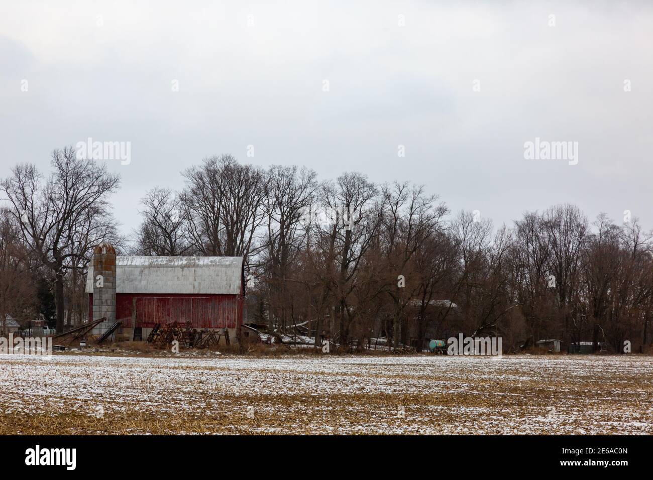 Junk umgibt eine Scheune an einem düsteren Wintertag in Leo-Cedarville, Indiana, USA. Stockfoto