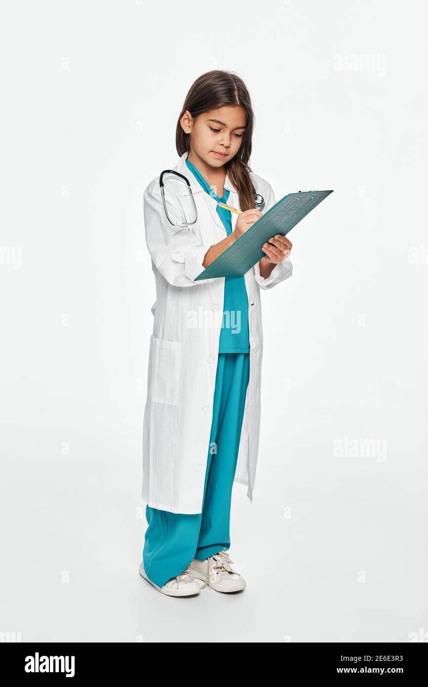 Ganzkörperportrait von Hispanic kleines Mädchen gekleidet als Arzt mit einem medizinischen Zwischenablage. Isoliert auf Weiß Stockfoto