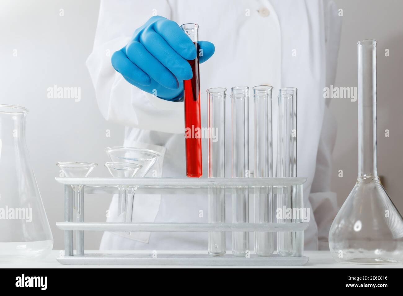 In einem chemischen Labor analysiert ein Apotheker ein Reagenzglas mit roter Flüssigkeit. Medizinisches Experiment. Ein Chemiker arbeitet an einem Test mit schutzgl Stockfoto
