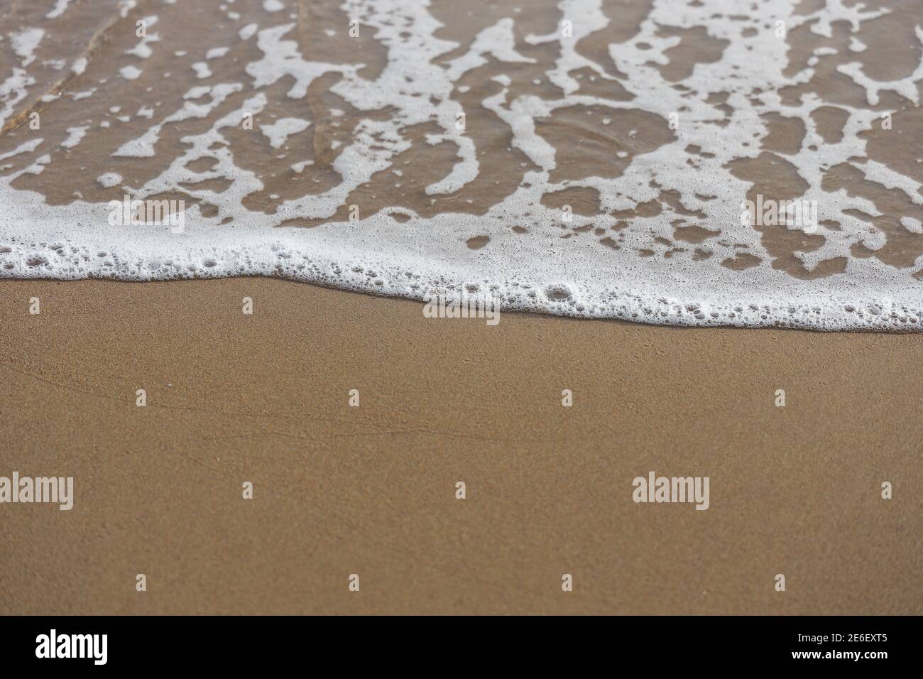 Weiche Wellen des blauen Ozeans am Sandstrand, Aqua Foam Blasen, Sommer Urlaub Hintergrund. Stockfoto