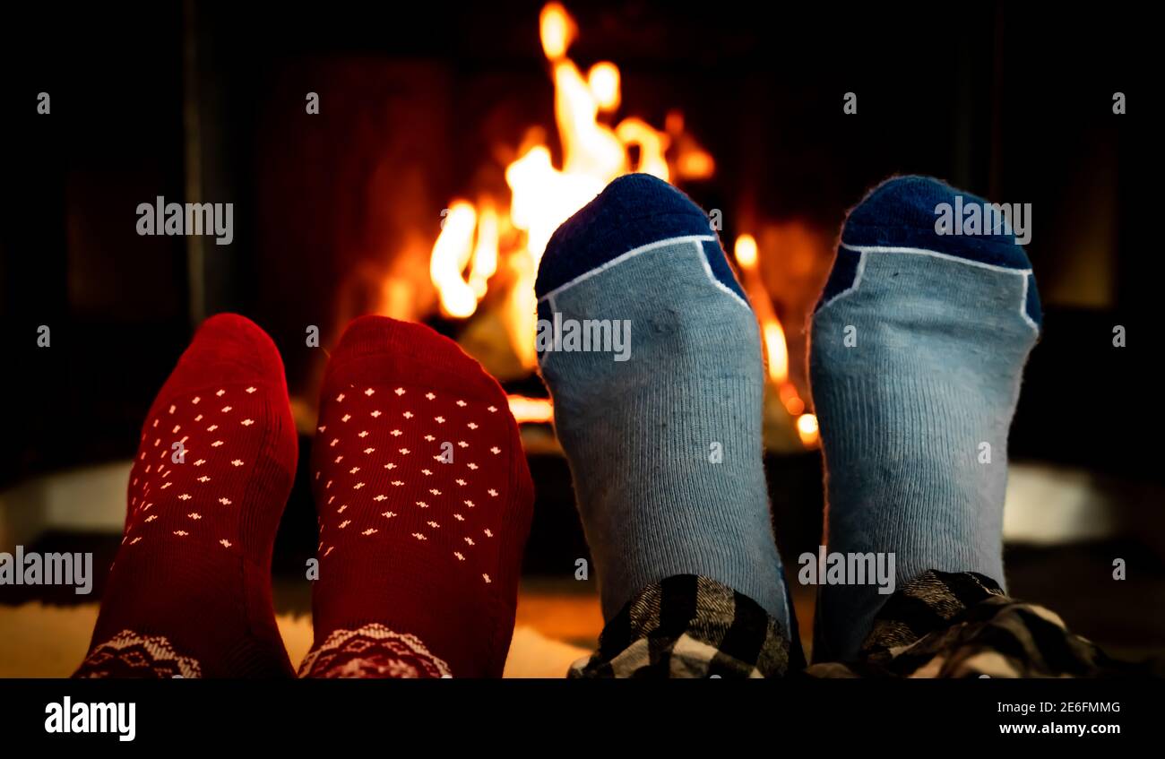 Füße in Wollsocken vor einem warmen Kamin an einem kalten Winterabend. Stockfoto