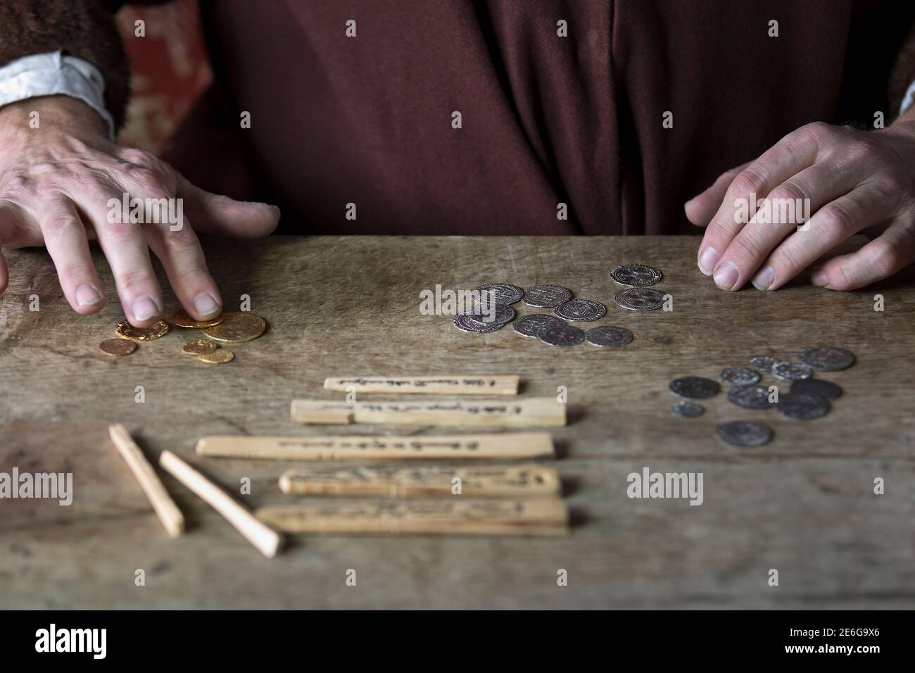 Mittelalterlicher Kaufmann, der Geld mit Tally Sticks zählt Stockfoto