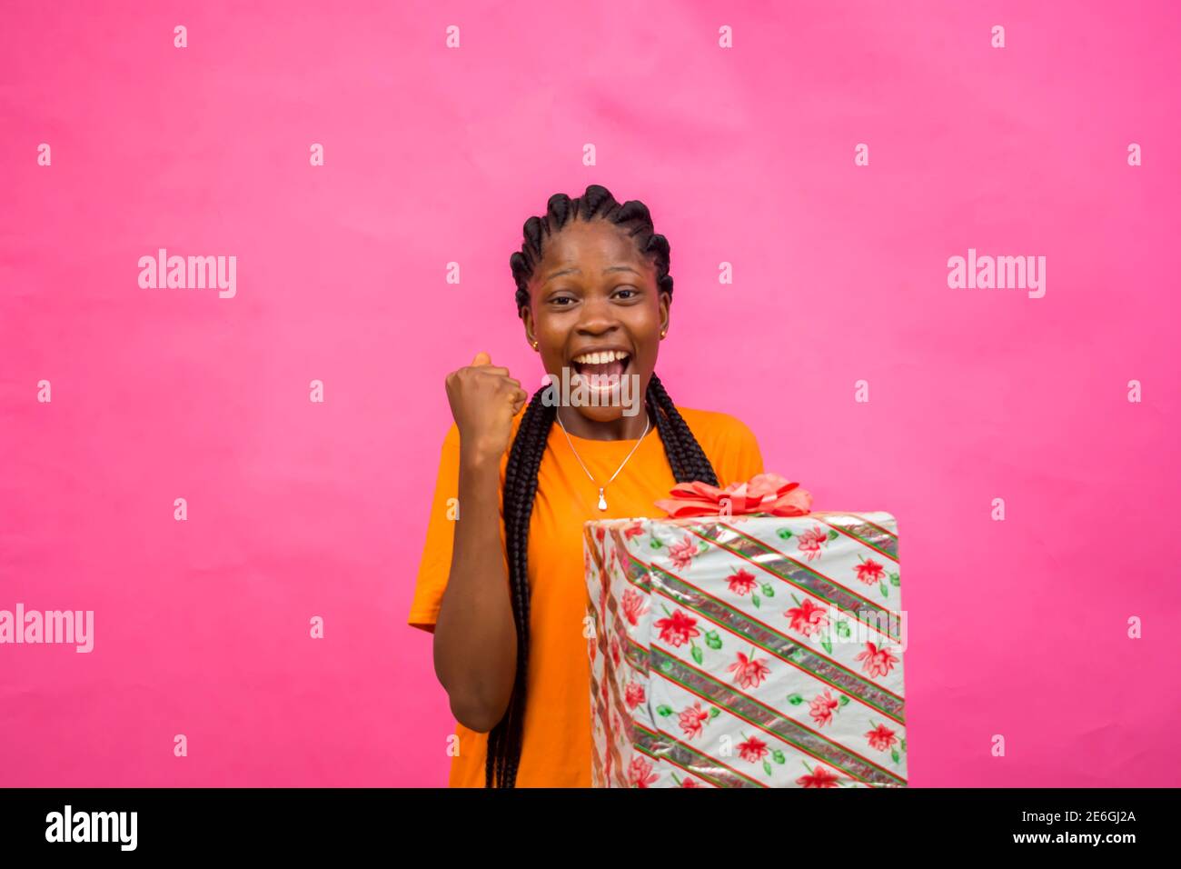 Junge schwarze schöne Dame mit einer eingepackten Geschenkbox Mit großer Freude Stockfoto