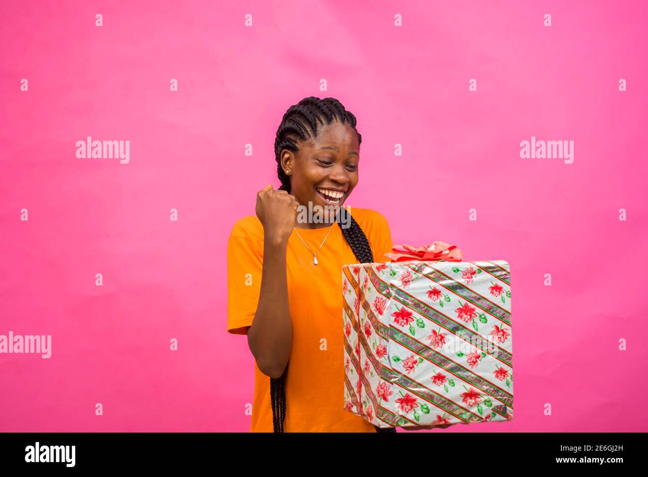 Junge schwarze schöne Dame mit einer eingepackten Geschenkbox Mit großer Freude Stockfoto