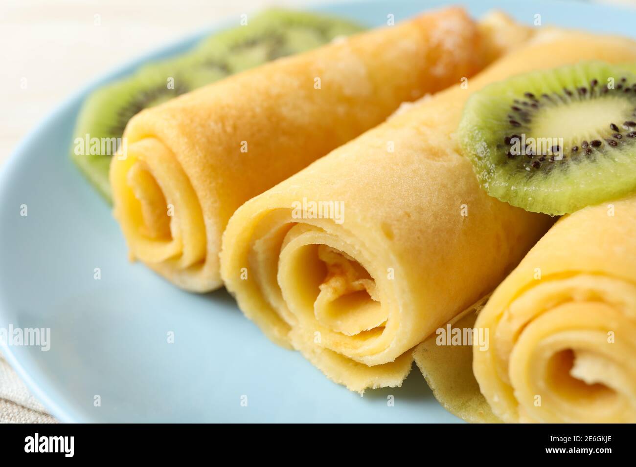 Platte mit Crepes-Rollen mit Kiwi-Scheiben, Nahaufnahme Stockfoto