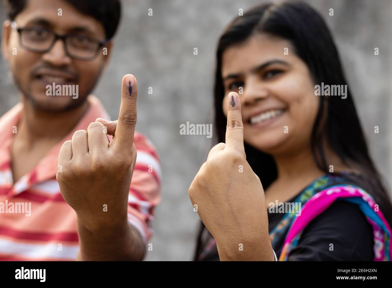 Indischer Mann und Frau, die mit Tinte markierte Finger mit lächelnden Gesichtern zeigen Nach der Abstimmung Stockfoto