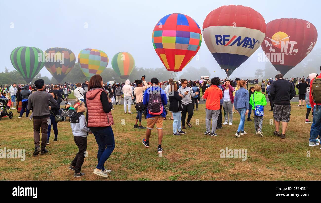 Ein Feld voller farbenfroher Heißluftballons, umgeben von einer Menschenmenge. Balloons Over Waikato Festival, Hamilton, Neuseeland Stockfoto