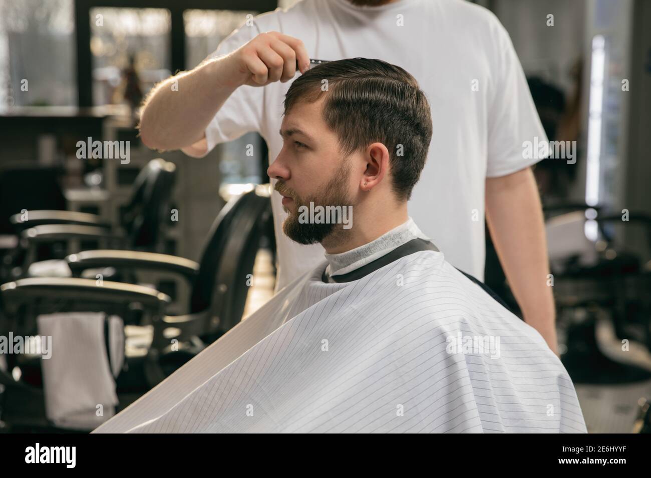 Nahaufnahme des Kunden von Master Barbier, Stylist während der Pflege und  neuen Look der Frisur. Beruf, männliche Schönheit und Selbstpflege-Konzept.  Weiche Farben und Fokus, vintage Stockfotografie - Alamy