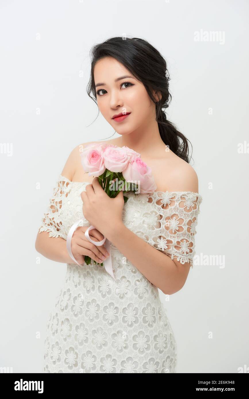 Wunderschöne junge Braut mit einem Rosenstrauß isoliert vor weißem Hintergrund. Stockfoto