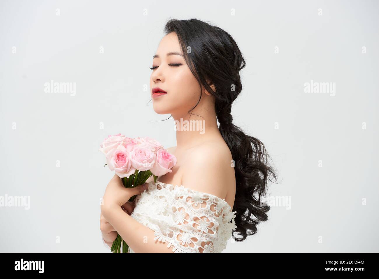 Schöne junge Braut im Hochzeitskleid mit Strauß auf weißem Hintergrund. Speicherplatz kopieren. Stockfoto