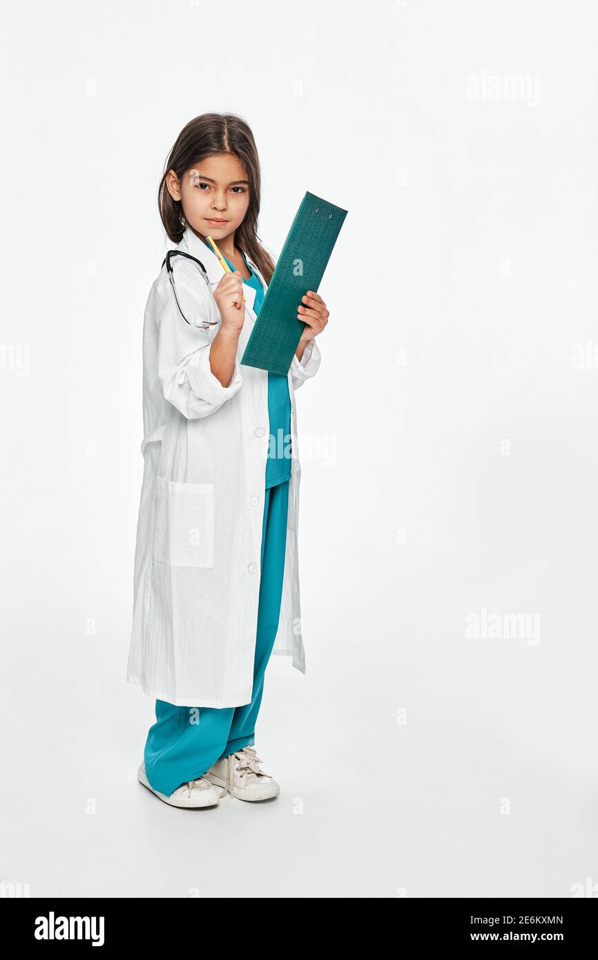 Kind spielt Arzt, zukünftiger Beruf. Cute hispanischen weiblichen Kind schreibt medizinische Behandlung auf ihre Zwischenablage. Weißer Hintergrund Stockfoto