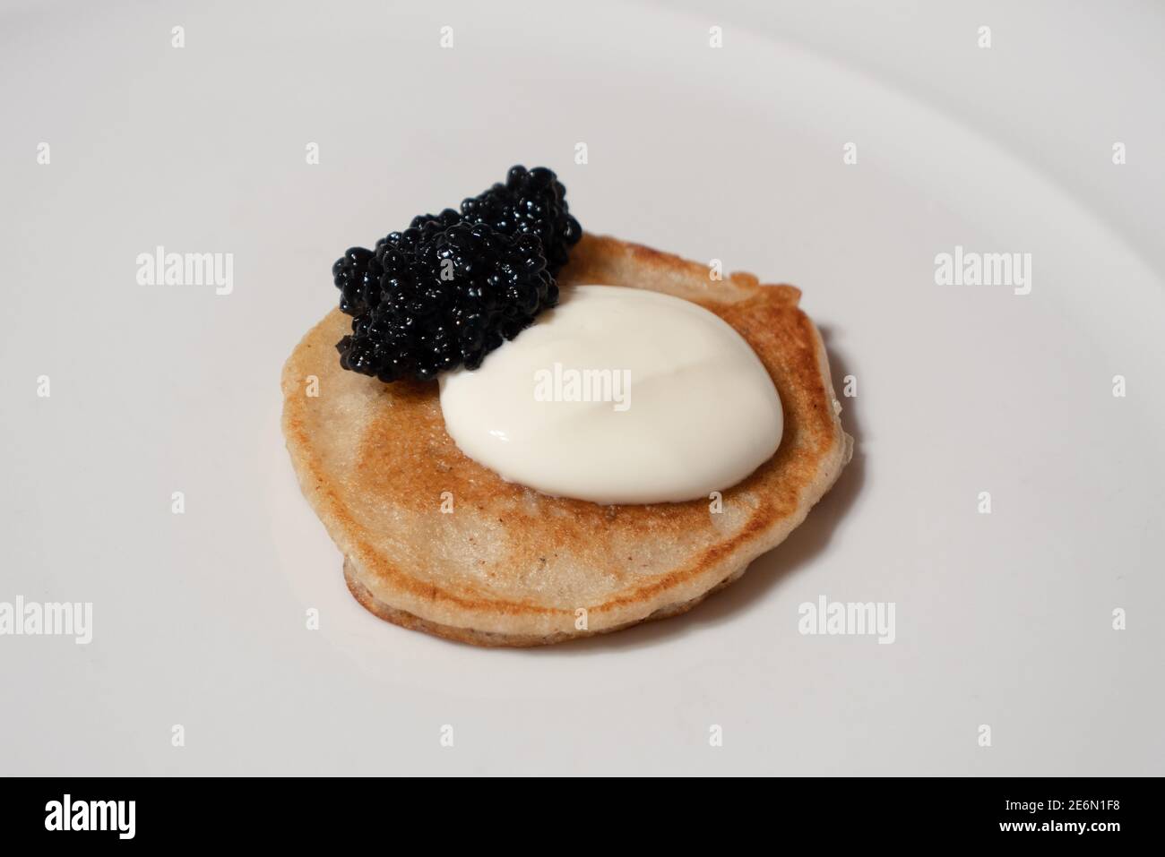 Eine schwarze Caviar Blini Buchweizen Pfannkuchen mit Sour Cream auf Eine weiße Platte Stockfoto