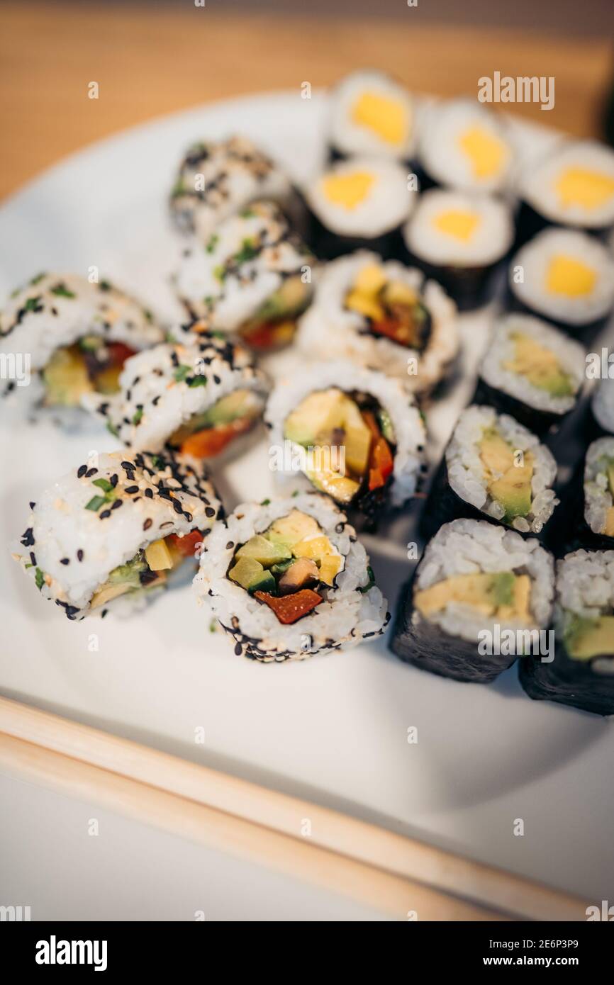 Set aus Sushi-Brötchen, Soße, Wasabi und Hand mit Essstäbchen auf dunklem Hintergrund. Draufsicht. Flach liegend. Japanisches Essen Stockfoto