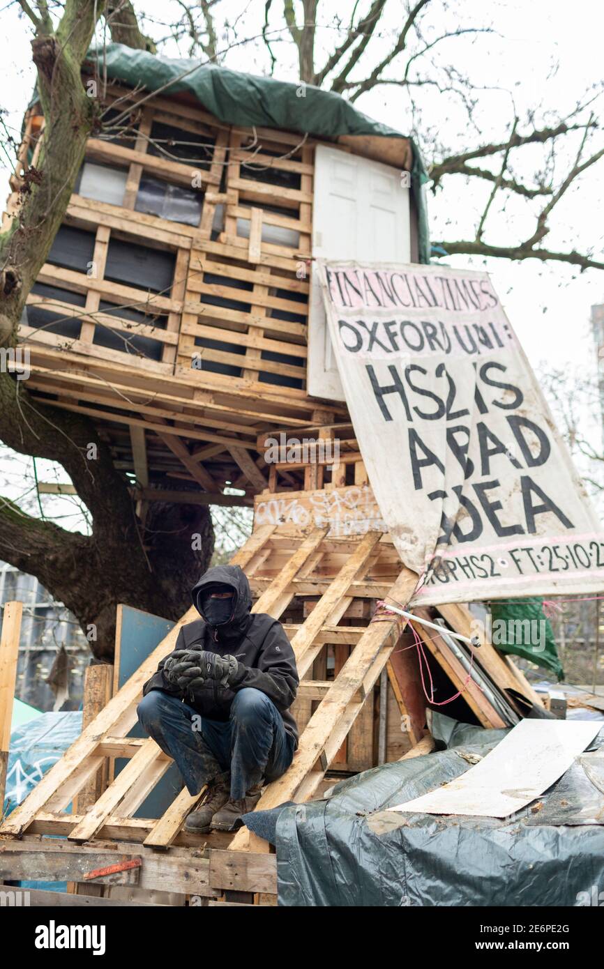 Räumung von Stop HS2 Demonstranten vom Campingplatz in Euston Square Gardens, London, 27. Januar 2021. Ein Protestler sitzt auf dem Dach einer Hütte im Lager. Stockfoto