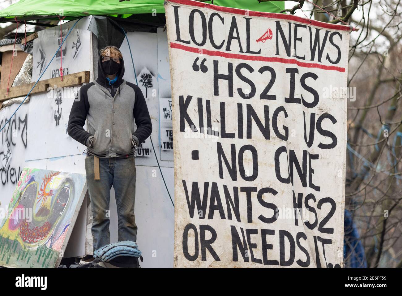 Räumung von Stop HS2 Demonstranten vom Campingplatz in Euston Square Gardens, London, 27. Januar 2021. Ein Protestler steht neben einem Banner im Lager. Stockfoto