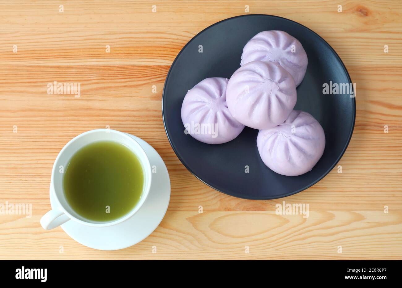 Tasse grünen Tee mit einem Teller Taro gedünstet Brötchen auf Holztisch Stockfoto