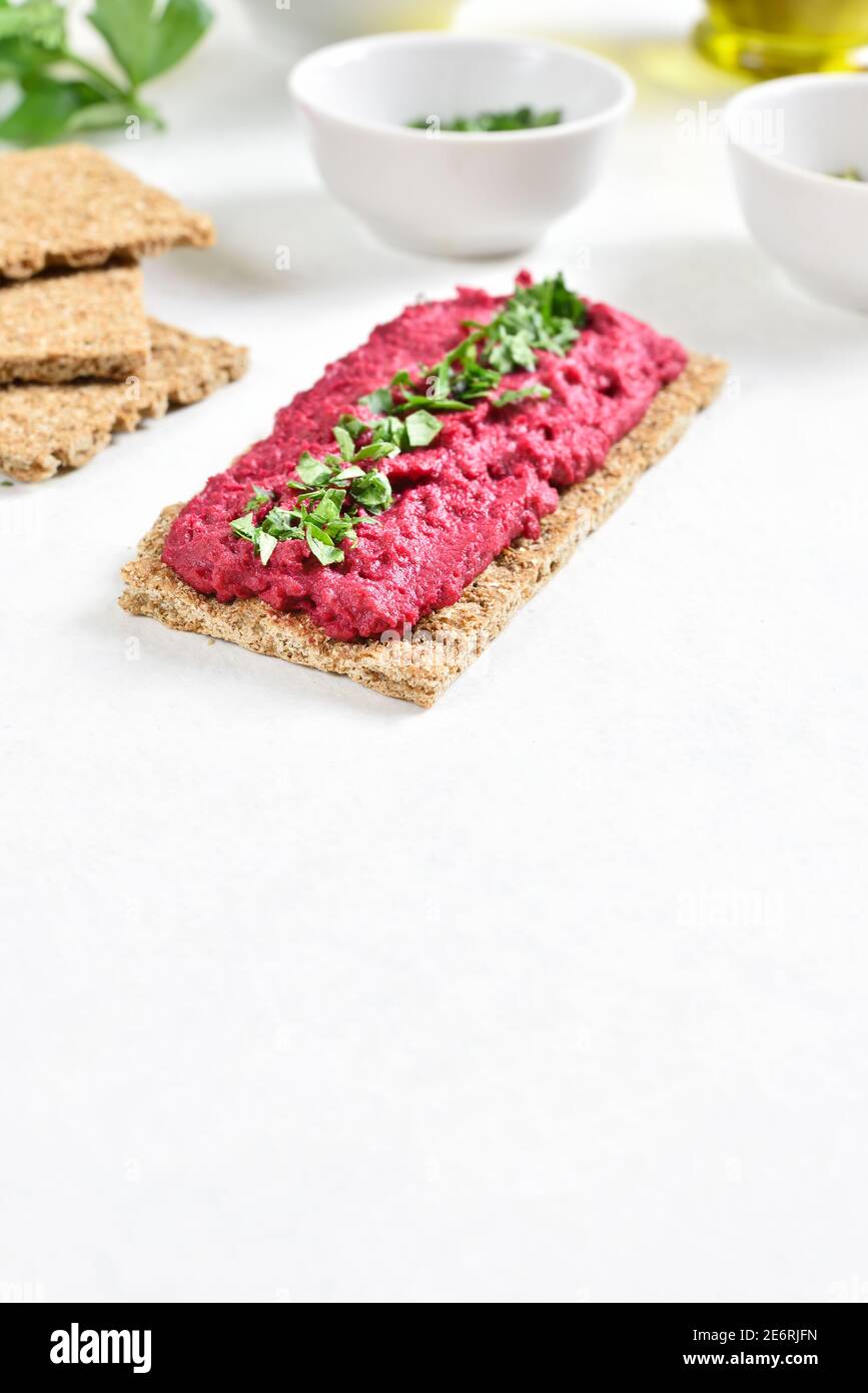 Hausgemachter Rübenhummus auf Brot auf weißem Stein Hintergrund mit freiem Textraum. Vegetarisches veganes Lebensmittelkonzept. Stockfoto