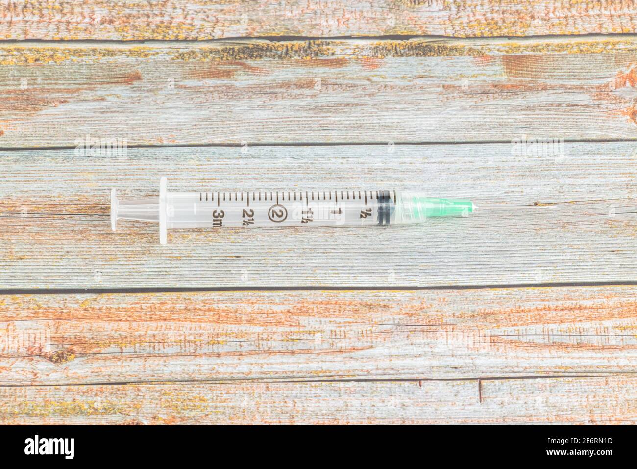 Eine Nahaufnahme mit selektivem Fokus auf einer hygienischen Einweg-Injektionsspritze aus Kunststoff, die auf einem Holztextur-Hintergrund steht. Stockfoto