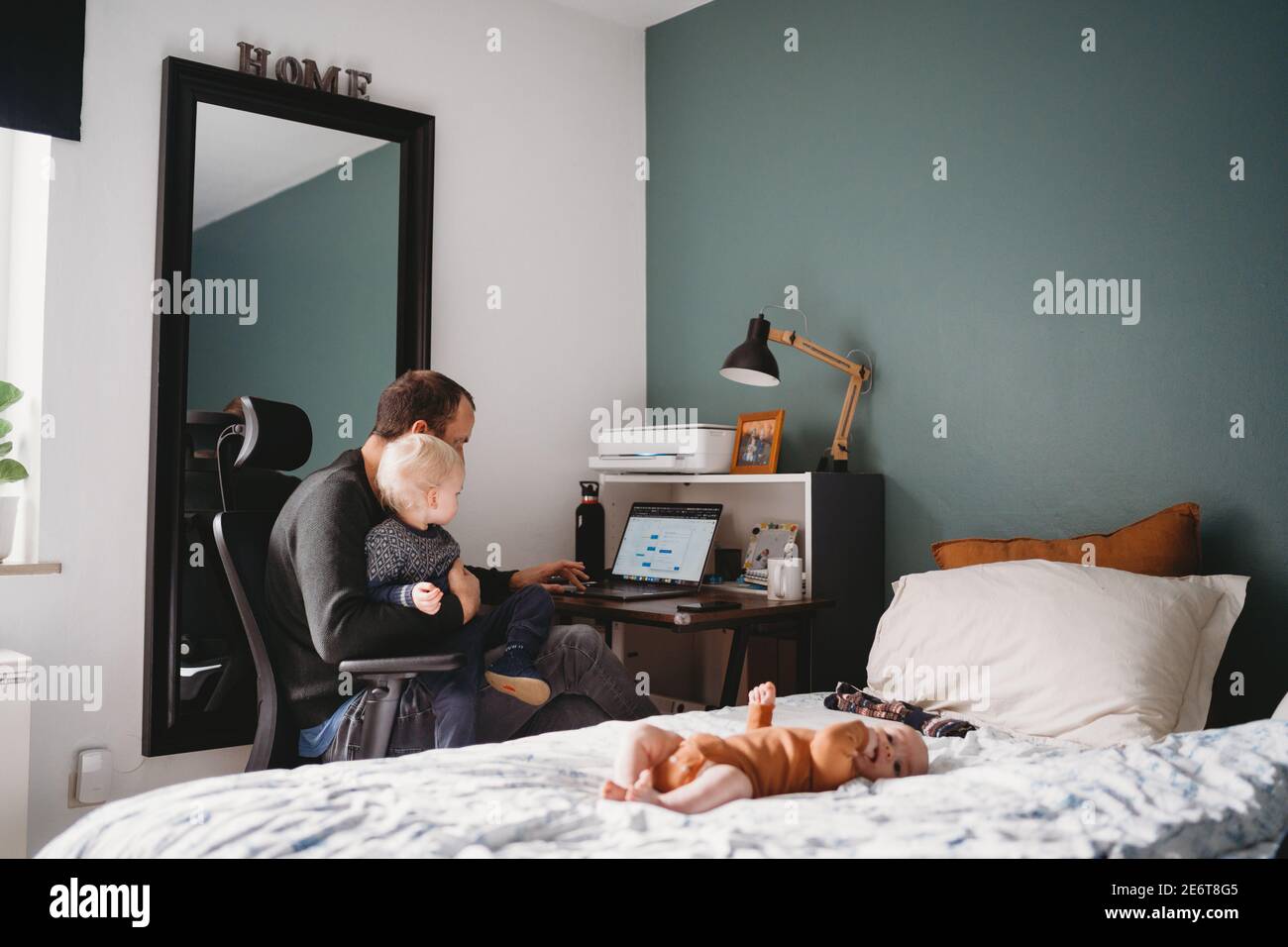 Papa mit Kind auf dem Schoß zu Hause Büro während covid Quarantäne Stockfoto