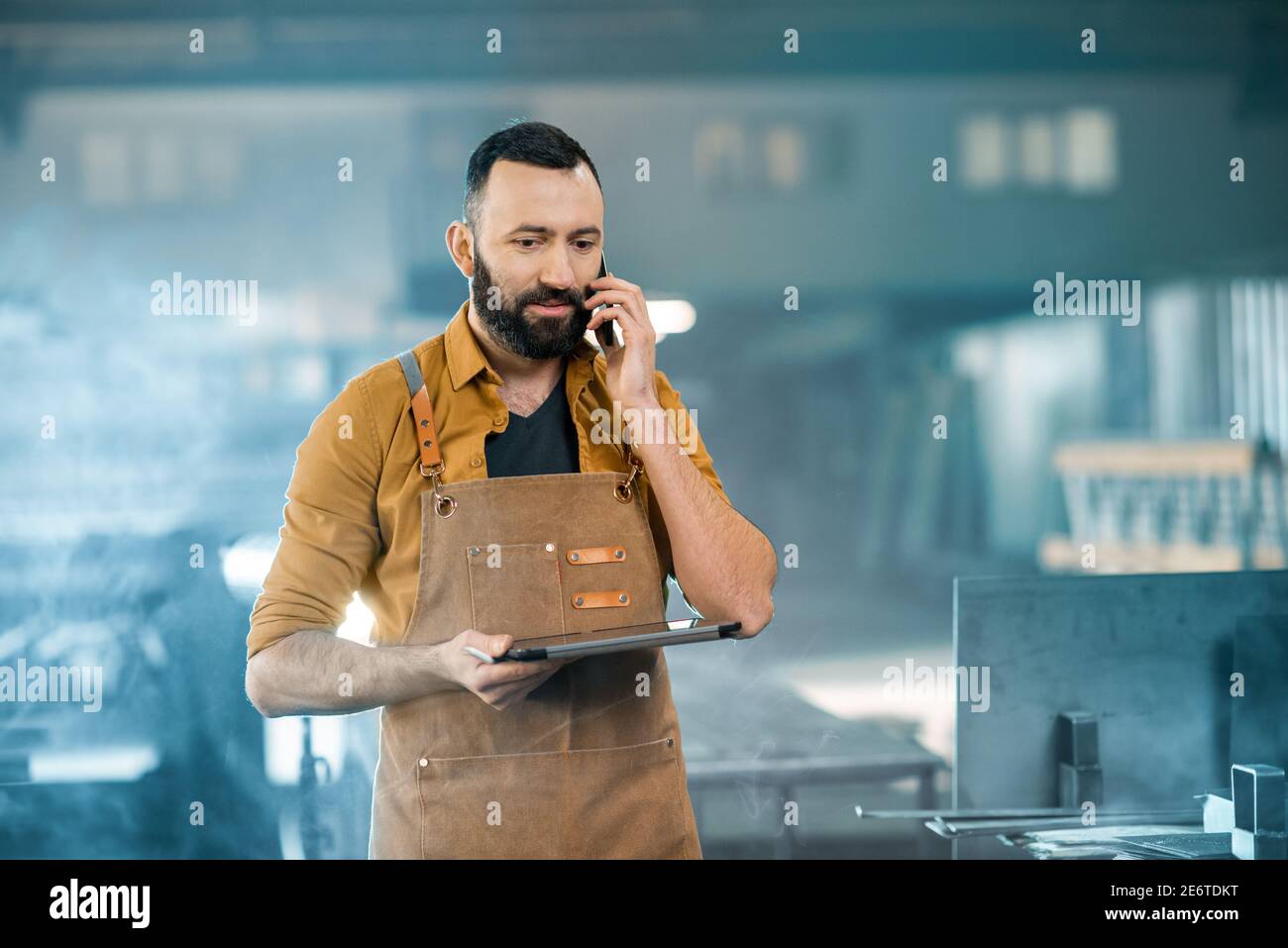 Fabrikarbeiter mit Tablet und Telefon bei der Fertigung Stockfoto