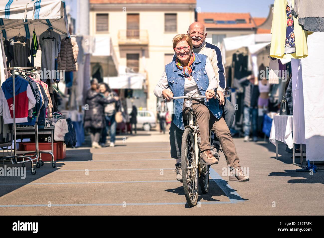 Glückliches Seniorenpaar, das Spaß mit dem Fahrrad auf dem Flohmarkt hat - Konzept der aktiven spielerischen Senioren mit Fahrrad während der Pensionierung - Alltagslebensfreude Stockfoto