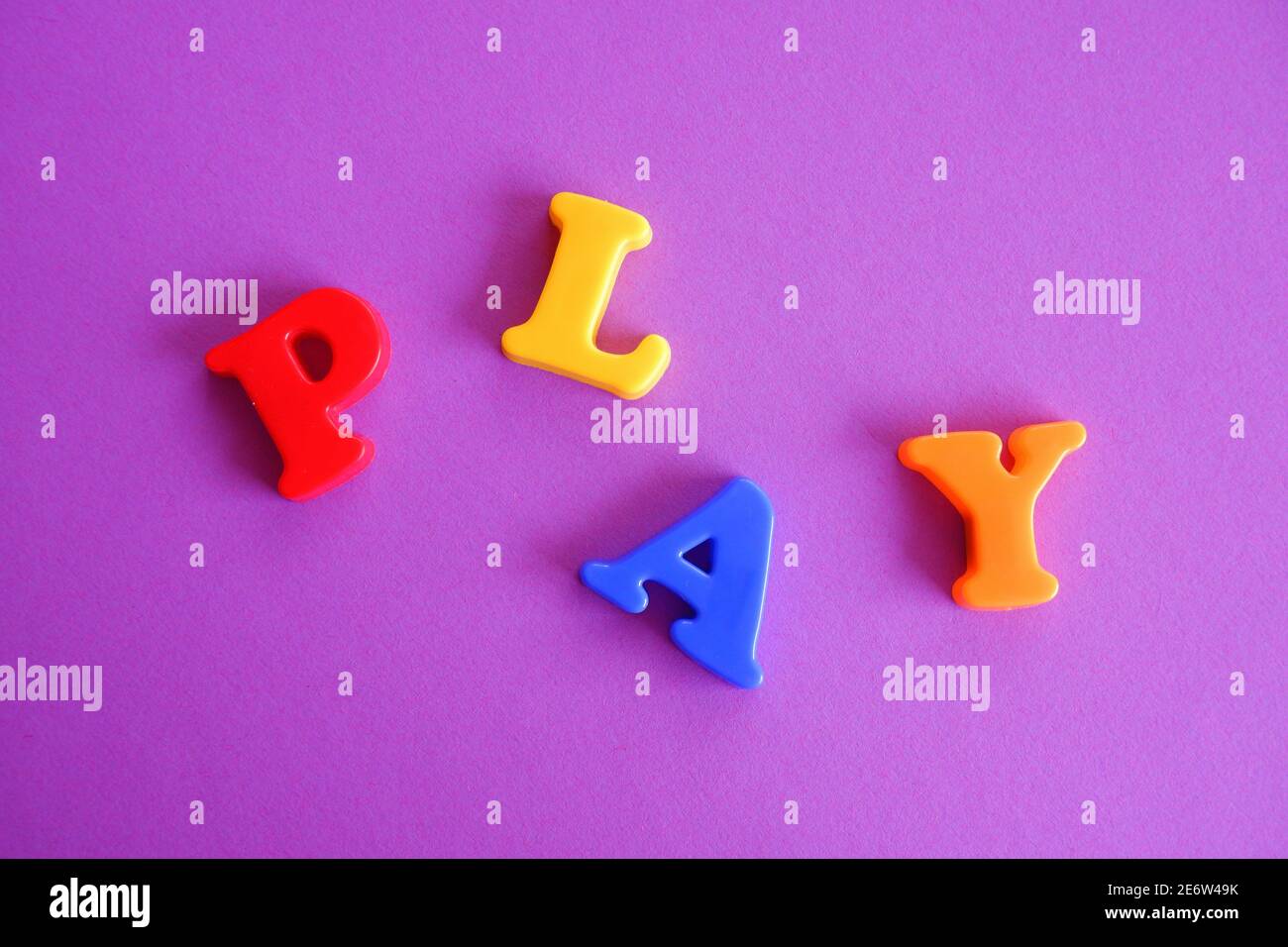 Spielen Wort in bunten Plastikbuchstaben auf einem rosa lila Hintergrund Stockfoto