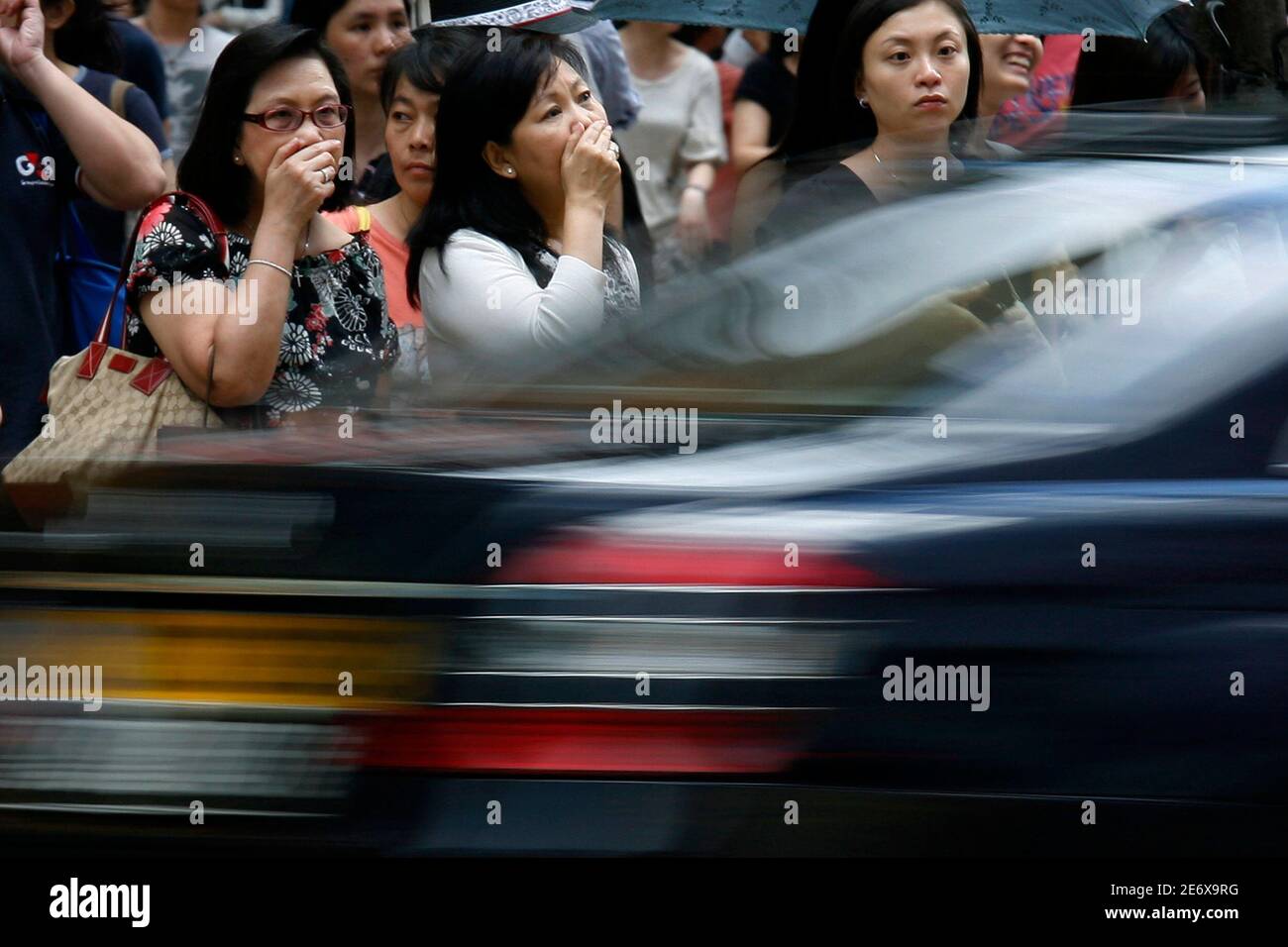 Die Käufer bedecken ihre Nase und Münder in der Nähe eines vorbeifahrenden Autos, während sie warten, um eine Straße im Einkaufsviertel Causeway Bay in Hongkong zu überqueren, 15. Juli 2009. Die städtische Umweltverschmutzung in Hongkong ist in den letzten vier Jahren sechsmal angestiegen, aber Experten sagen, dass lokale Fahrzeuge mehr schuld sind als Smog, der aus den Produktionsbändern Südchinas hereingeweht wurde, berichtete eine Zeitung am Mittwoch. REUTERS/Bobby Yip (CHINA POLITICS BUSINESS ENVIRONMENT) Stockfoto