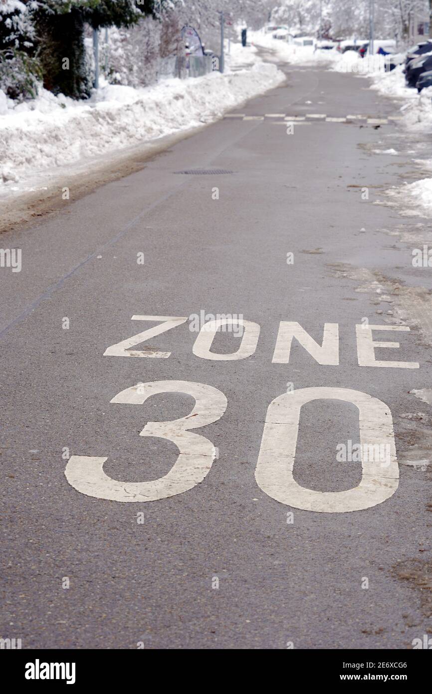 Zone 30 km pro Stunde reduzierte Geschwindigkeit im Dorf Urdorf in der Schweiz im Winter. Auf beiden Seiten der Straße gibt es jede Menge Schnee. Stockfoto