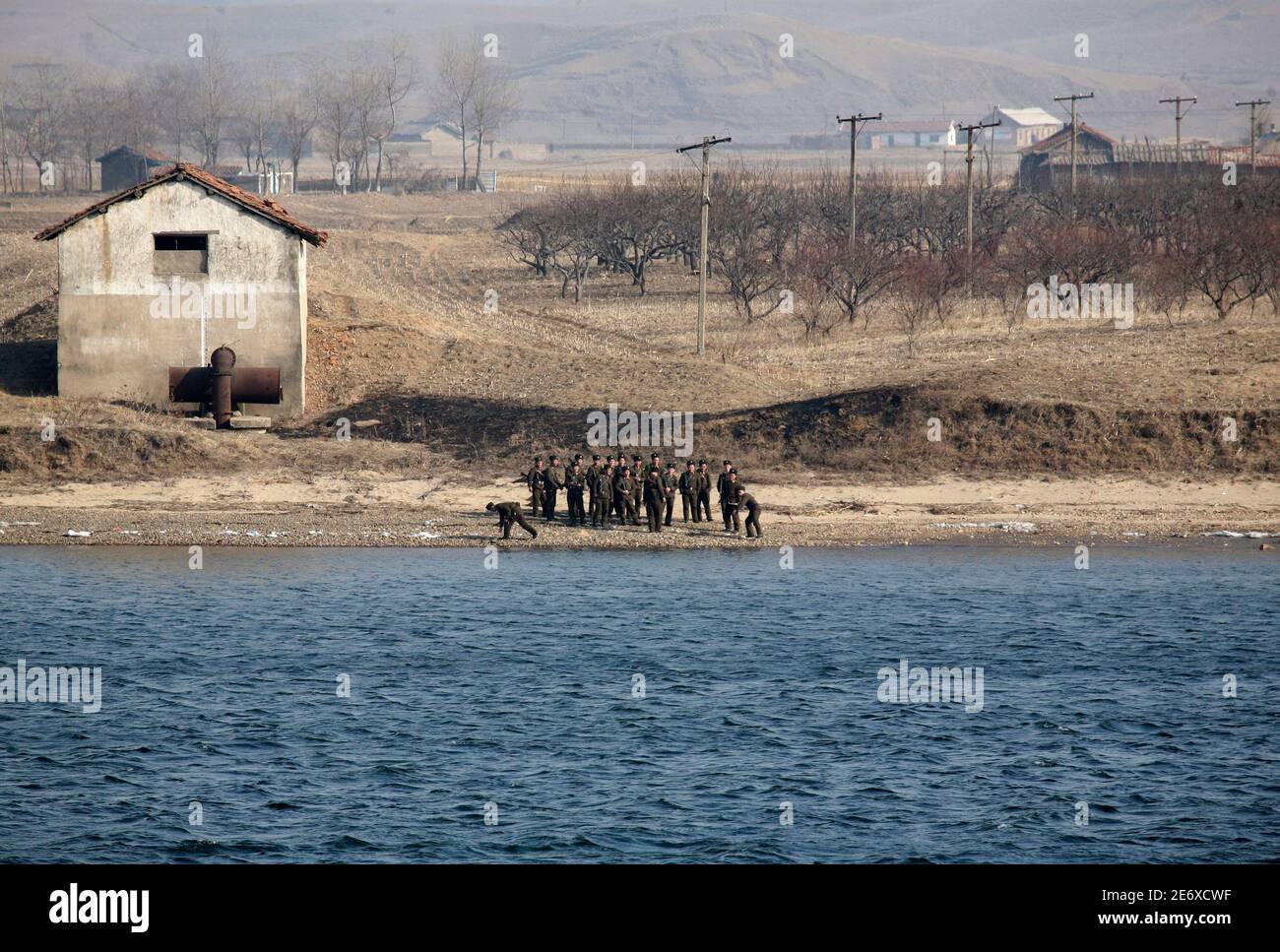 Nordkoreanische Soldaten spielen mit Steinen und bewachen die Ufer des Flusses Yalu in der Nähe der nordkoreanischen Stadt Sinuiju gegenüber der chinesischen Grenze Stadt Dandong, 10. März 2010. China einen 10-Jahres-Mietvertrag der Expertenkommission Anschluss an Nordkoreas Ostküste, potentiell erhöht Versand Zugang zum Meer von Japan, erworben hat, sagte eine provinzielle offizielle während Chinas legislative Jahrestagung. REUTERS/Jacky Chen (Nordkorea - Tags: MILITÄRGESCHÄFT Politik) Stockfoto