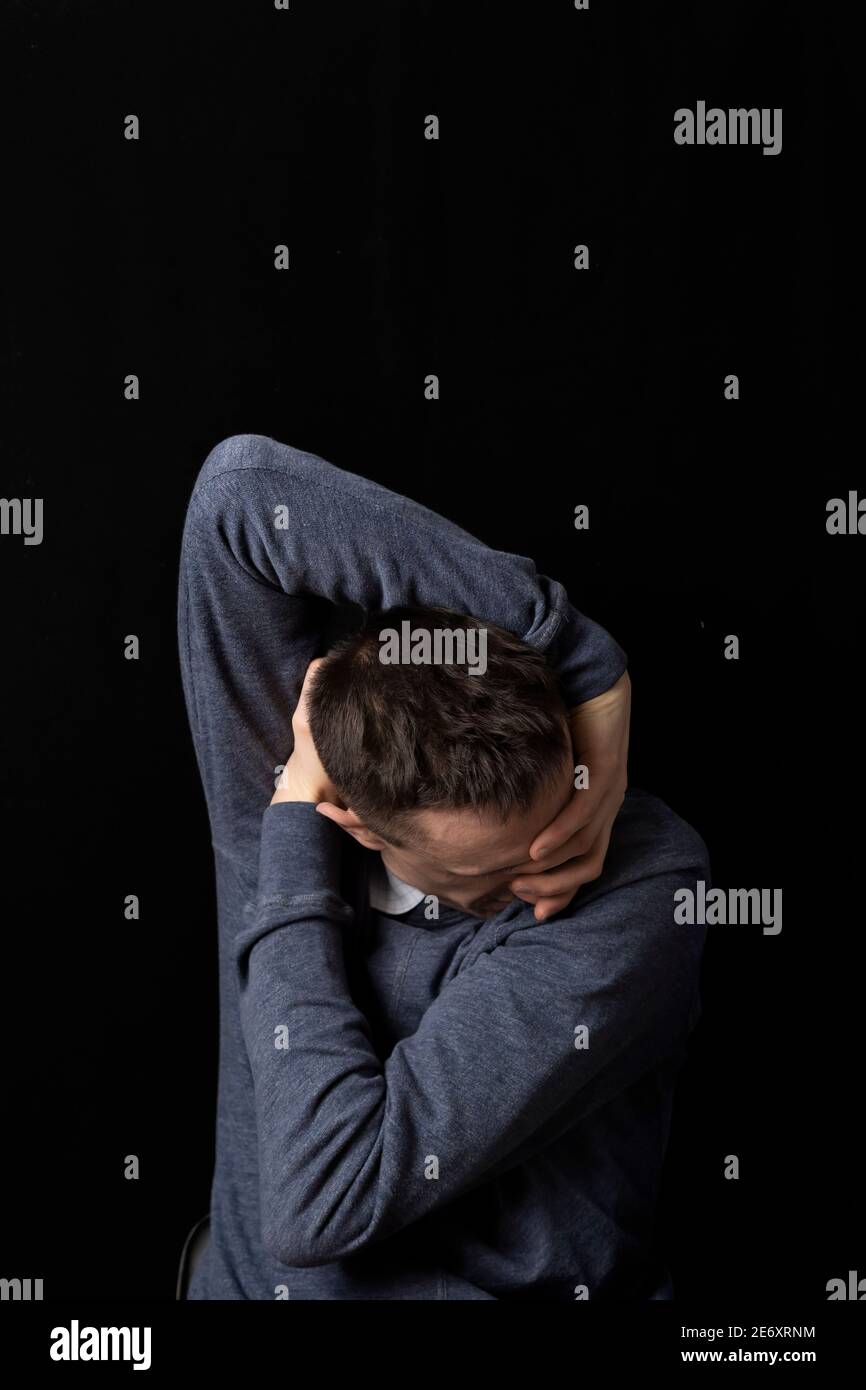 Psychische Gesundheit. Ein Mann in einem deprimierten Zustand auf einem schwarzen Hintergrund. Trauriger Mann. Stockfoto