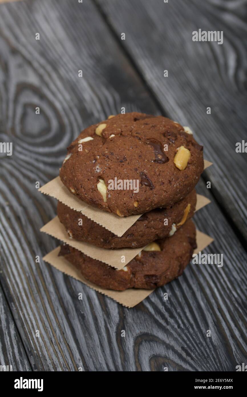 Haferflocken Kekse mit Erdnüssen und Schokolade. In einer Säule gefaltet und mit Papier ausgelegt. Auf Kiefernbrettern. Stockfoto
