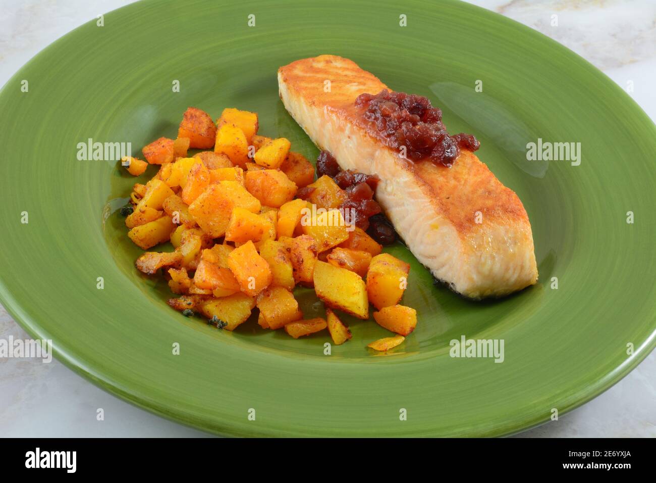 Gegrilltes Lachsfilet mit Cranberry-Sauce und Butternut-Kürbis Mit Gewürzen Abendessen auf grünem Teller Stockfoto