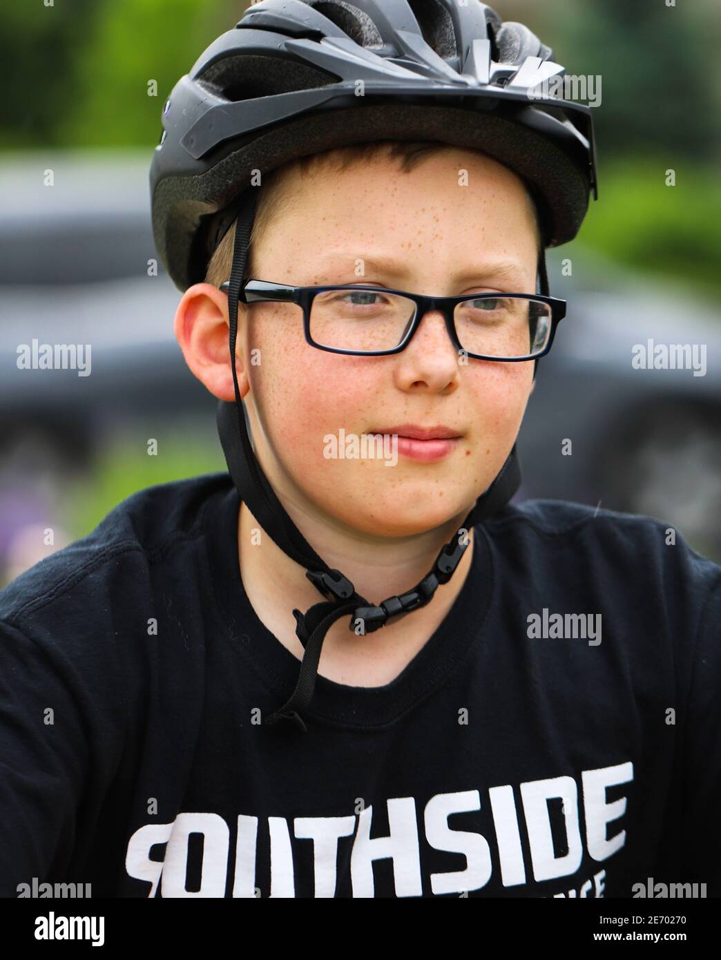 Junge gut aussehende fair gehäutet preteen Junge trägt ein schwarzes Fahrrad Helm und dunkle Brille sehen zuversichtlich für den Start Das Rennen Stockfoto