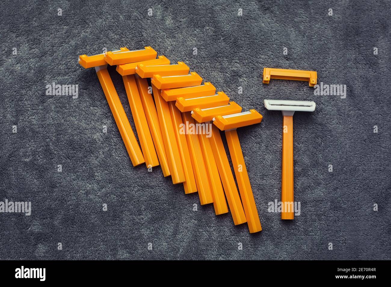 Viele Kunststoff Einweg billig rasieren orange gelb Rasierer mit Kappen auf  grauem Hintergrund, Haarentfernung Werkzeuge Set Stockfotografie - Alamy