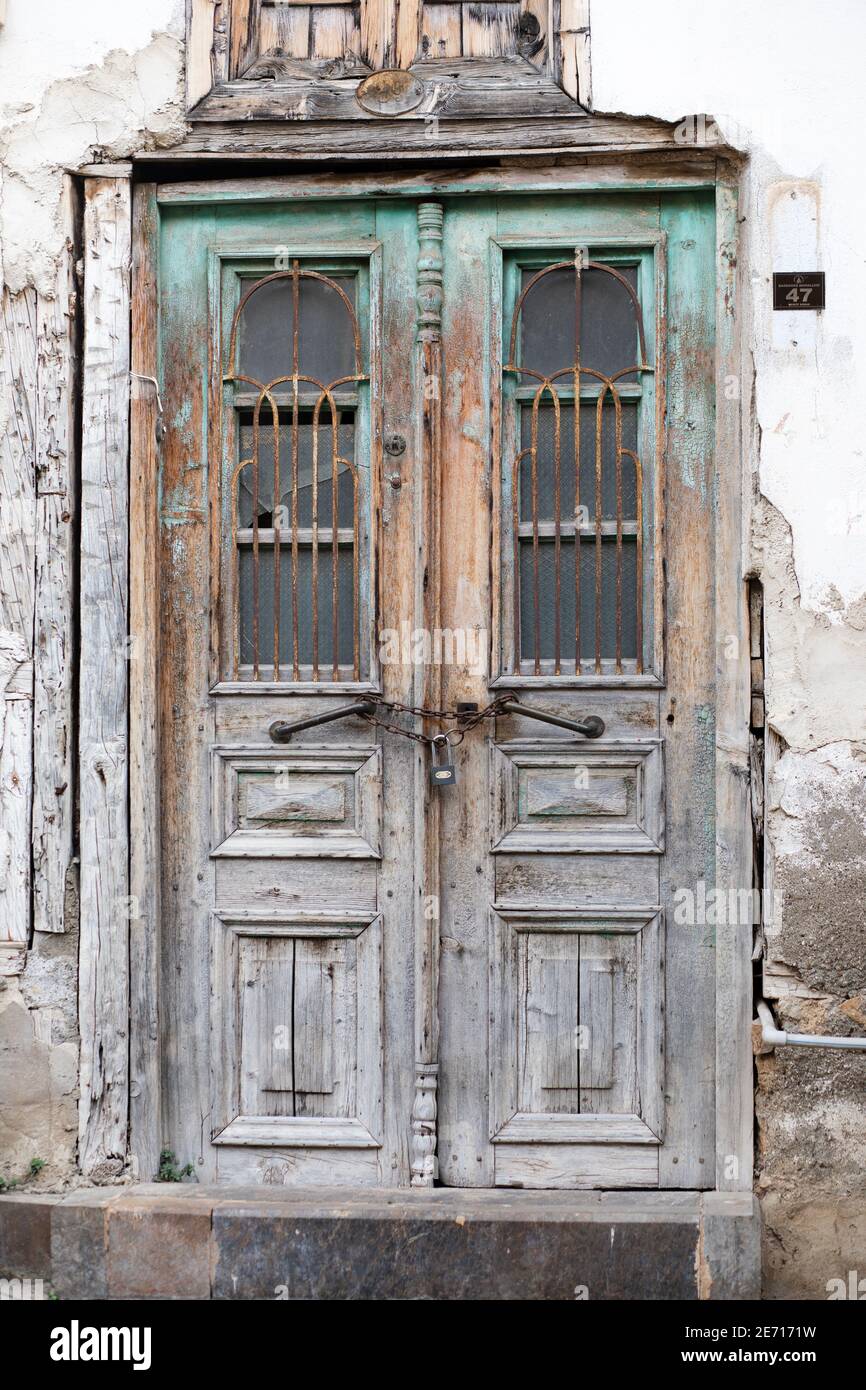 Antike Holztür mit geschnitzten Einsätzen, Muster aus Metallstangen und  Glas. Abblätternde grün-blaue Farbe und Kette und Schloss. Vertikale  Aufnahme. Antalya, Türkei Stockfotografie - Alamy