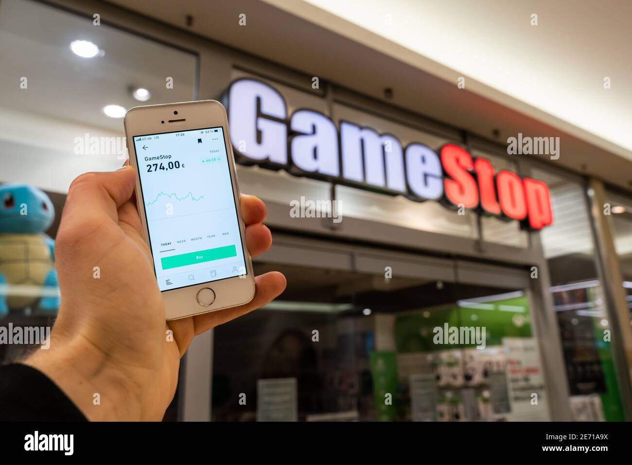 GameStop GME Aktie in der Online-Broker Trading App Trade Republic auf einem Handy-Bildschirm. Vor einem GameStop-Store stehen. Stockfoto