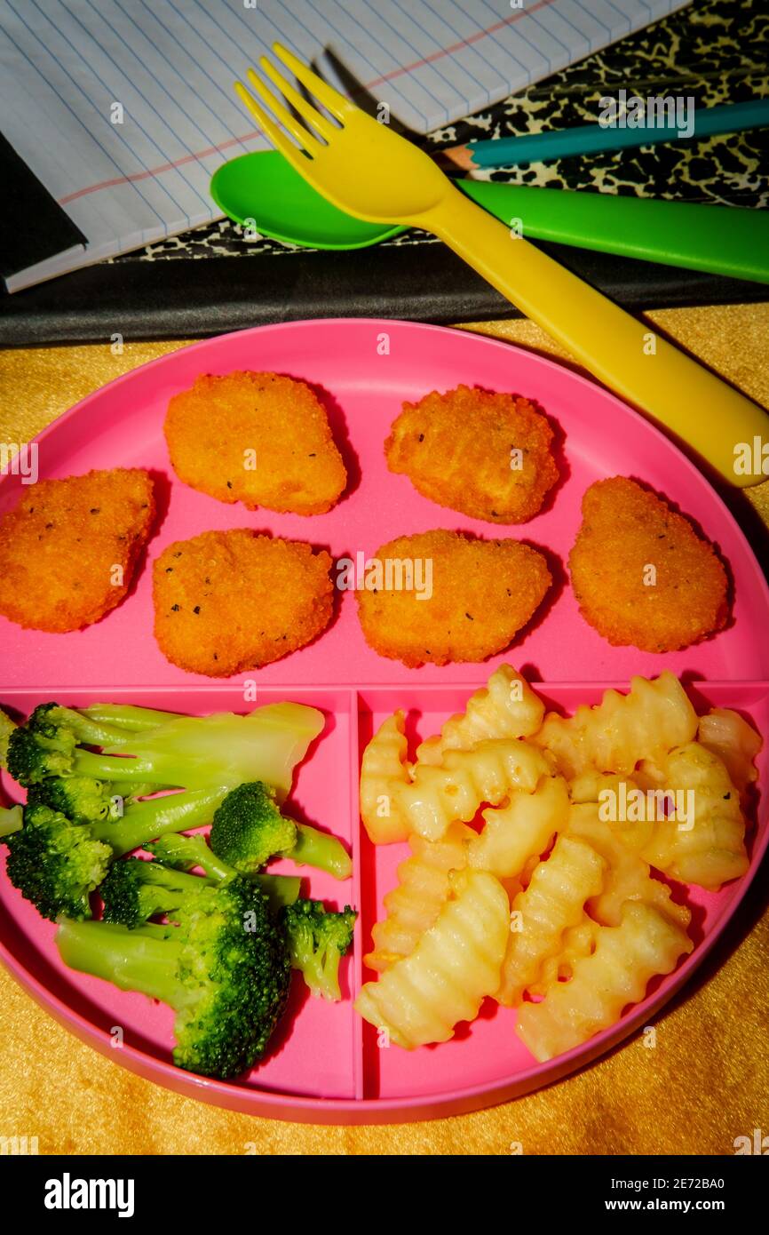 Zu Hause Schule Huhn Nugget Mittagessen auf Tablett mit serviert pommes Frites und Brokkoli Stockfoto