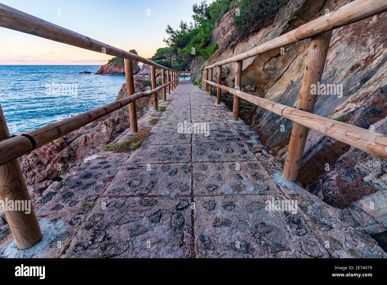 Ich gehe bei Sonnenuntergang mit Holzgeländern an der Küste entlang Stockfoto