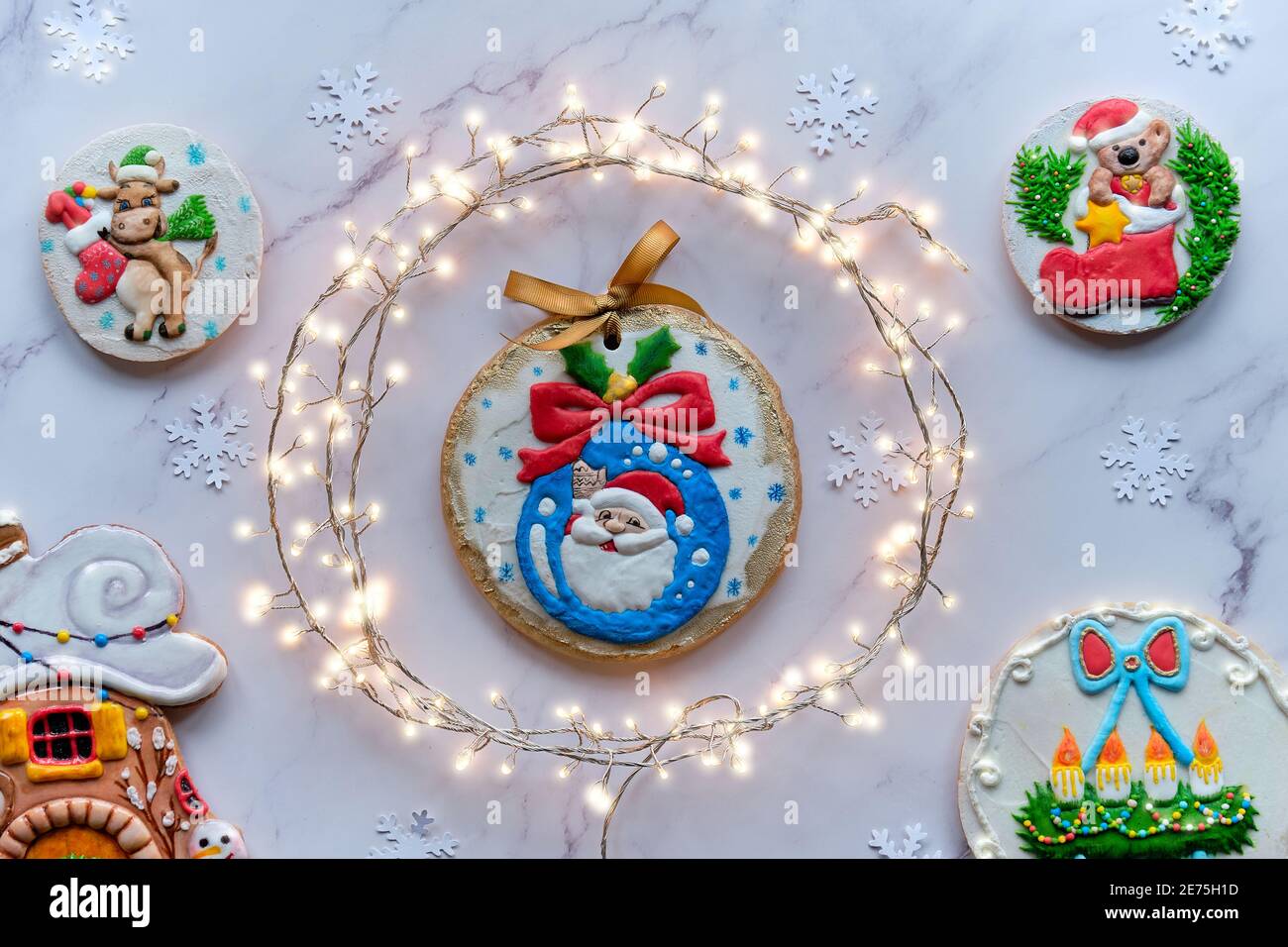 Dekorierter Lebkuchen mit verschiedenen Motiven, Sortiment von leckeren traditionellen Kindergeschenken für Weihnachten. Weihnachten Draufsicht mit festlicher Girlande im Kreis Stockfoto