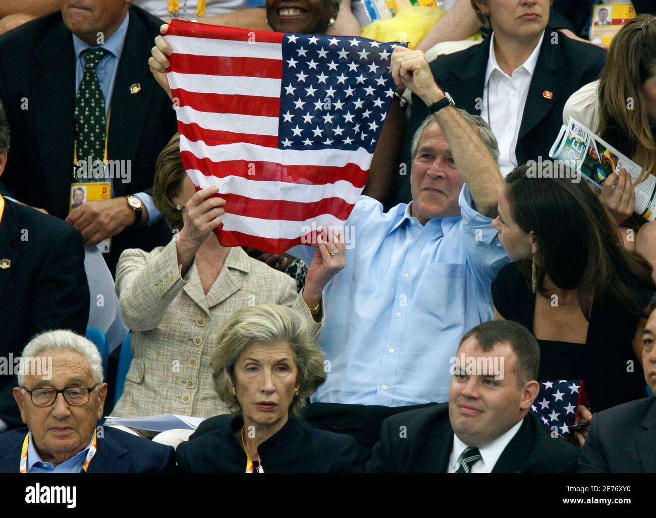 U.S. President George W. Bush (C) hält die US-Flagge als First Lady Laura Bush es passt und Tochter Barbara auf im National Aquatics Center vor dem Schwimmen Wettkampf während der Beijing 2008 Olympischen Spiele August 10, 2008 blickt. An der Unterseite sind ehemalige US-Außenminister Henry Kissinger (L) und seine Frau Nancy.     REUTERS/Jerry Lampen (CHINA) Stockfoto