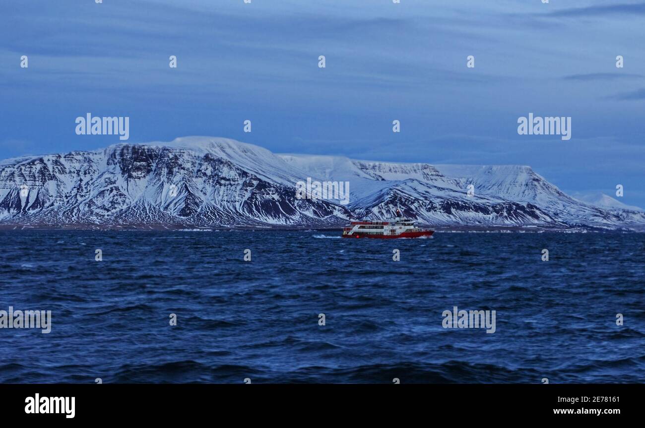 Echt rotes hübsches Schiff in der Winterdämmerung bei isländischen Felsen Stockfoto