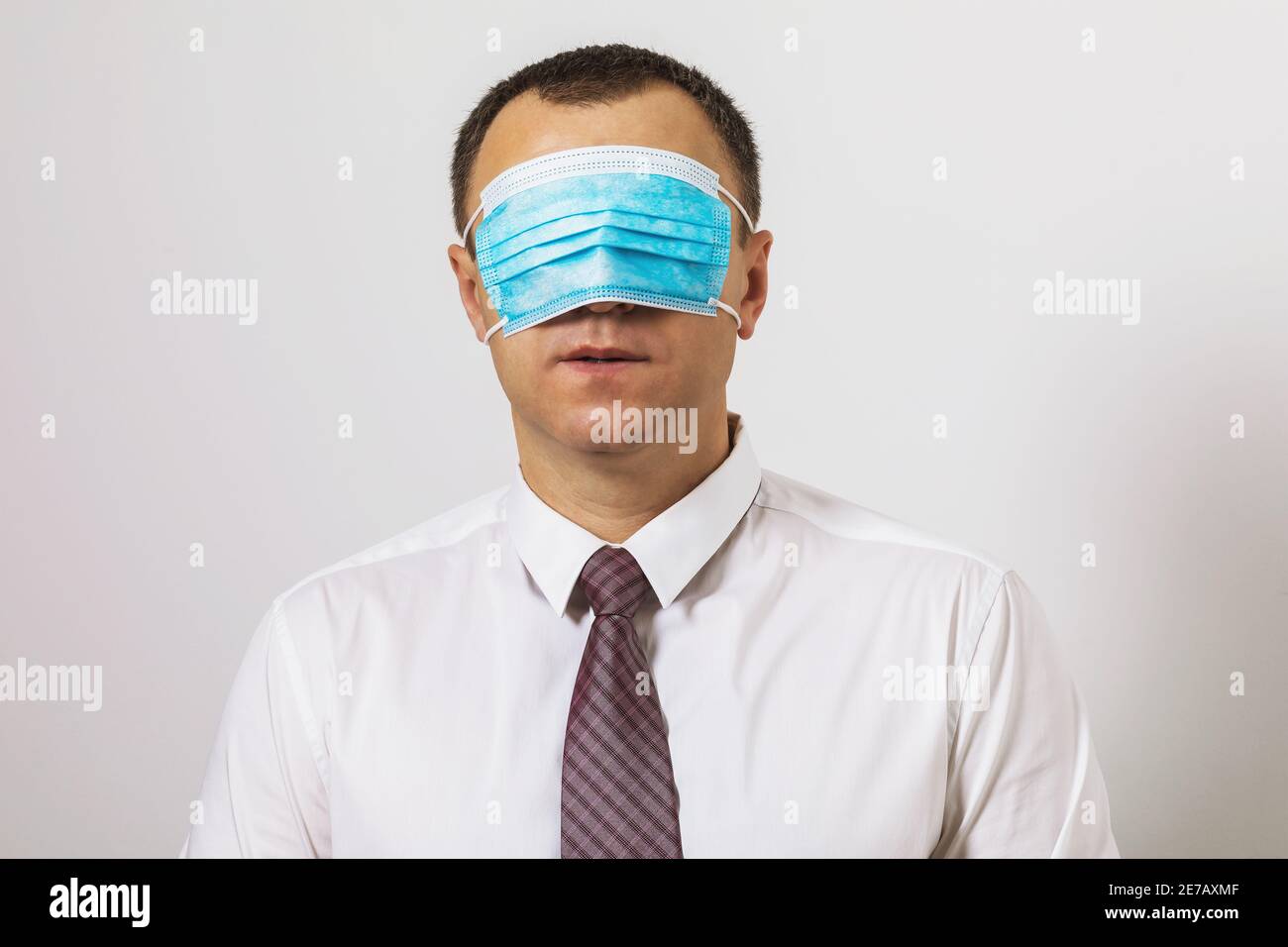 Büroangestellter mit einer medizinischen Maske auf den Augen vor dem Hintergrund der Wand. Stockfoto