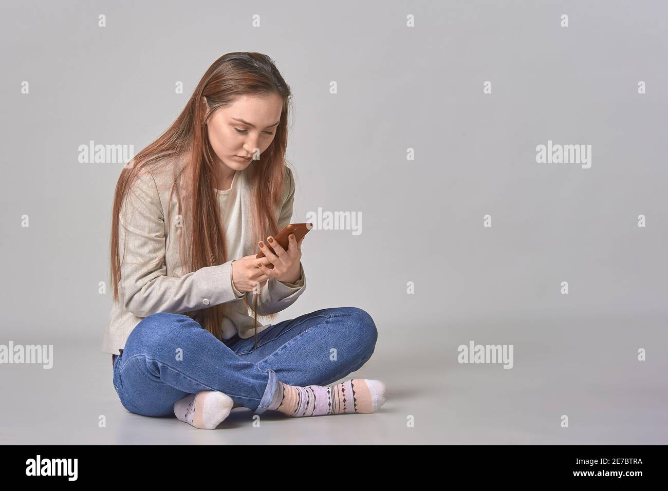 Ein Mädchen liest Botschaften auf weißem Hintergrund in ihr Telefon Stockfoto