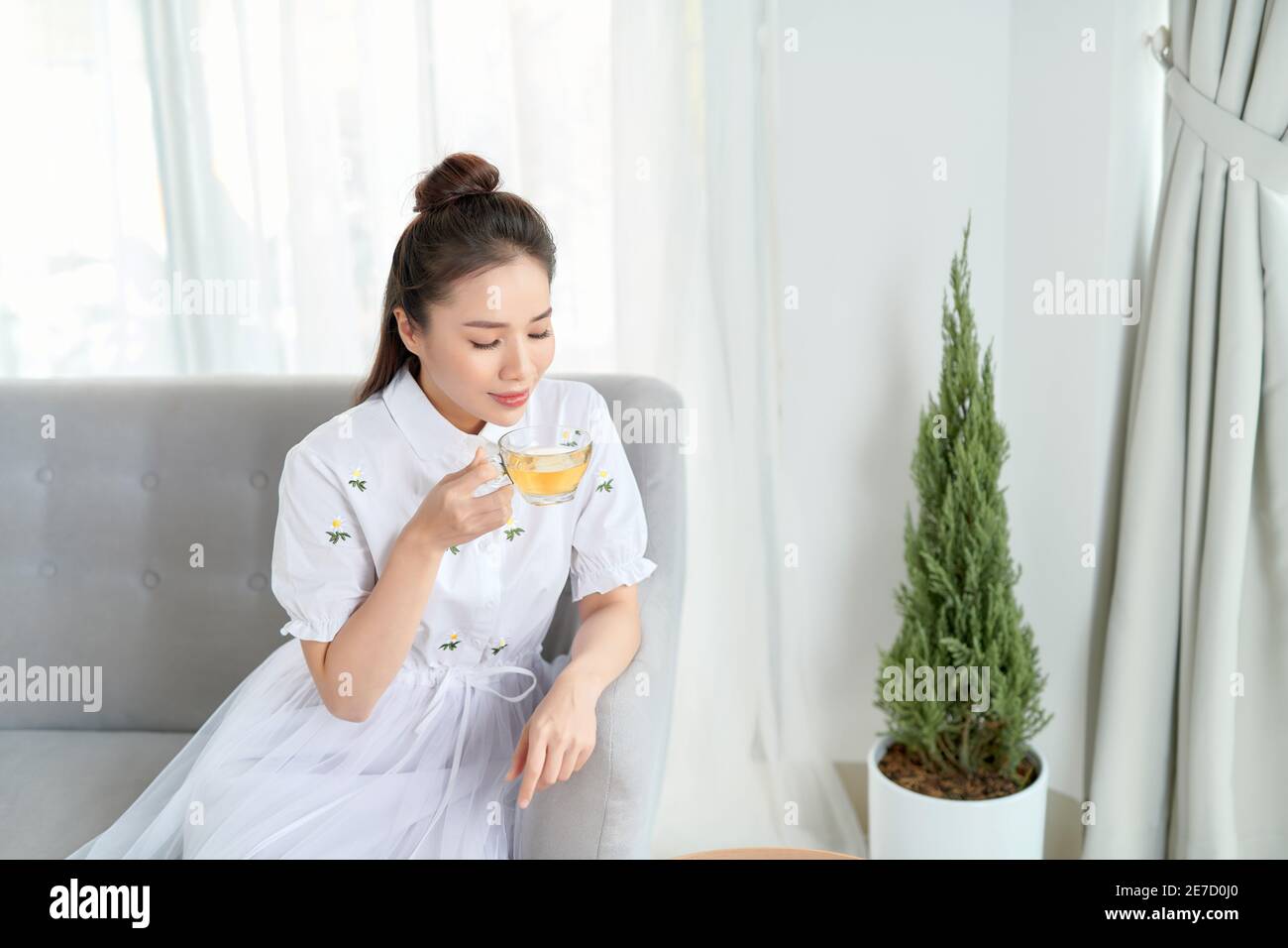 Innenaufnahme einer lächelnden asiatischen Frau, die Tee trinkt. Stockfoto
