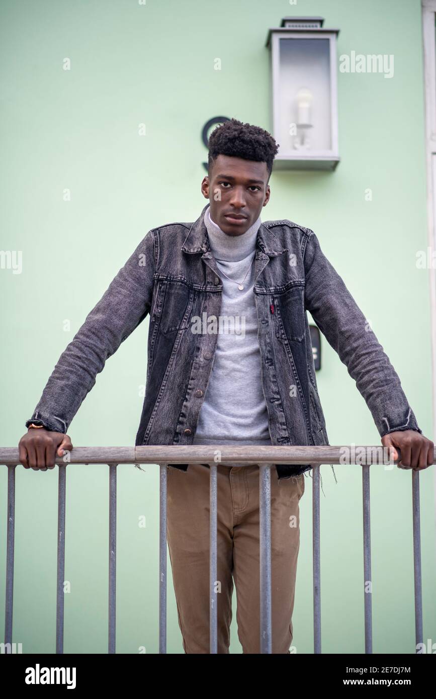 Vertikale Aufnahme von jungen schwarzen Mann lehnt an Geländer Stockfoto