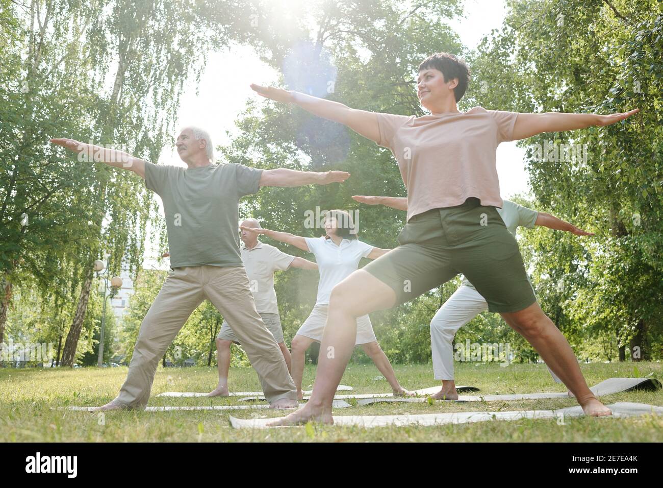 Gruppe von Menschen, die auf grünem Gras stehen und Sport treiben Gemeinsam im Park im Freien Stockfoto