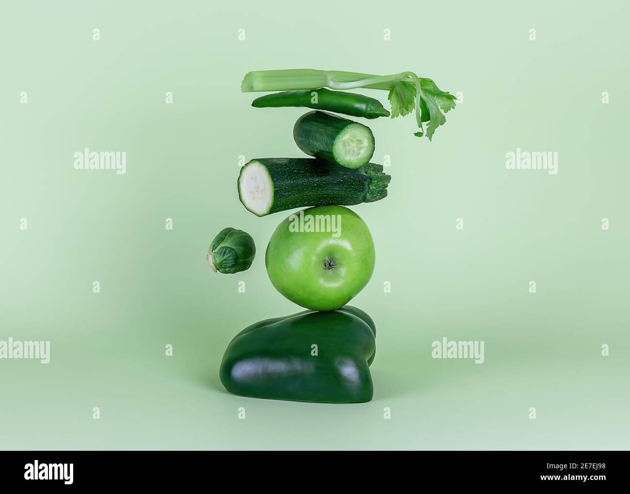 Frisches grünes Gemüse und Obst auf grünem Hintergrund. Gleichgewicht schwimmende Lebensmittelbalance. Stockfoto